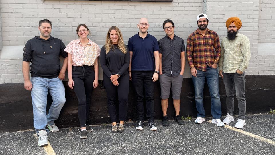 A group of Upanup employees posing against a brick wall.