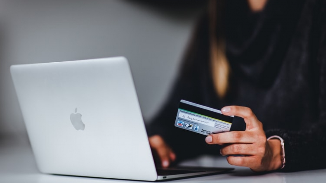 Holding a credit card by laptop for ecommerce