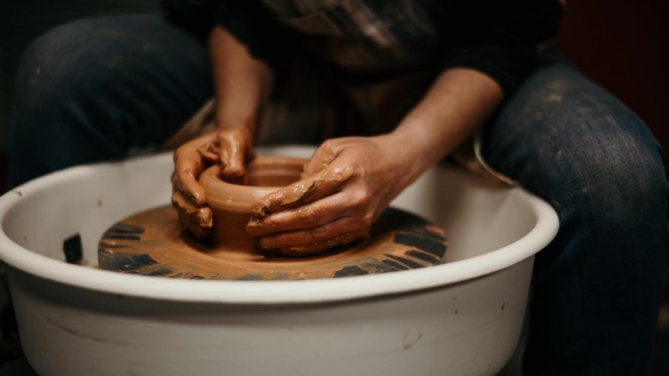 Hands creating clay bowl. 