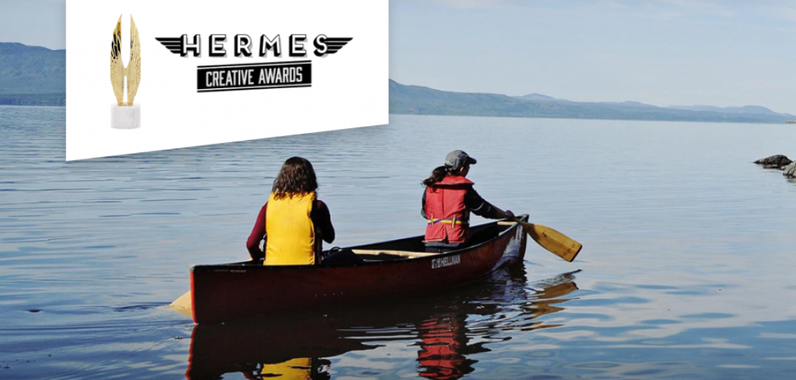 Two people canoeing on a lake by mountains.